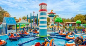 World of PAW Patrol Is Almost Here at Chessington! Bumper boats ride in a colorful theme park, with riders in orange and blue boats circling a central striped tower.