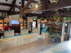 New Look, Same Warm Welcome: Gulliver’s Hotel Reveals Refreshed Reception Hotel reception area with three wooden check-in desks, wicker pendant lights, and tropical plants.