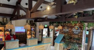 New Look, Same Warm Welcome: Gulliver’s Hotel Reveals Refreshed Reception Hotel reception area with three wooden check-in desks, wicker pendant lights, and tropical plants.