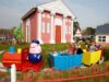Grandpa Pig’s Little Train to Close Briefly for Essential Maintenance Colorful children's train ride with a Peppa Pig figure, red engine and blue/yellow cars, carrying families past a pink building.
