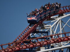 Happy 32nd Birthday to The Big One – The Roller Coaster That Changed Britain Forever A roller coaster car full of riders on a red track at Pleasure Beach under a clear blue sky.