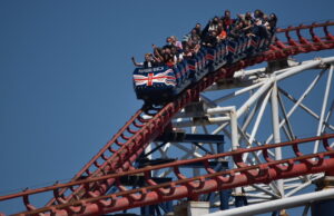 Happy 32nd Birthday to The Big One – The Roller Coaster That Changed Britain Forever A roller coaster car full of riders on a red track at Pleasure Beach under a clear blue sky.