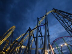 Late Night Rides Are Back This May Half-Term at Fantasy Island Nighttime view of illuminated roller coasters with yellow and blue tracks twisting against a dark blue sky