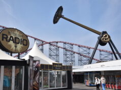 AVIKTAS Is Finally Open at Blackpool Pleasure Beach — And It Was Worth the Wait Large outdoor amusement area with a circular 'Pleasure Beach Radio' sign and red roller coaster tracks in the background.