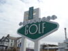 Save 50% on Adventure Golf at Blackpool Pleasure Beach Large green-and-white sign reading 'Adventure Golf' at a seaside resort, with a 'Pleasure Beach' emblem above.