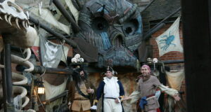 We Can’t Be the Only Ones Still Missing the Pirate Show in Mutiny Bay Three performers in pirate costumes center stage in a steampunk pirate set with a large mechanical creature face above and skulls nearby.