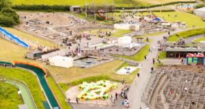 Dinosaur Park Near Tenby Listed for £4 Million Aerial view of a large outdoor amusement park with water slides, play structures, and families walking along paved paths.