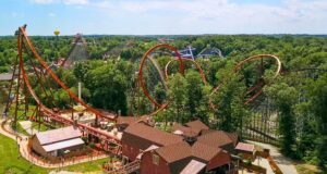 Holiday World Opens Its Gates for an Incredible 80th Season Celebration Aerial view of a forested amusement park with orange roller coasters and wooden rides interwoven among trees.