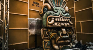 Step Inside the Forbidden Chamber: Movie Park Germany’s New Attraction Large carved totem head with bold facial features inside a studio with metal truss structures surrounding it