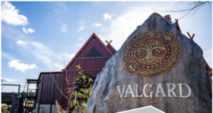 Why Valgard and Aviktas Make May 2026 a Must-Visit Month for Theme Parks Viking-themed amusement park entrance with a large carved rock and wooden buildings behind a roller coaster framework.