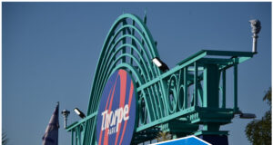 Could Cedar Point’s “Morning Rush” Concept Work at UK Theme Parks? Entrance sign at Cedar Point with teal arches and a roller coaster structure against a blue sky as riders zoom by above the track.