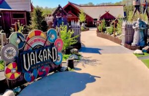 Could We Be Stepping Into the UK’s Best Theme Park Land at Paultons Park on May 16th? VALGARD Might Just Change Everything Entrance to a Viking-themed attraction with a colorful shield-decorated sign and wooden fences along a paved path.