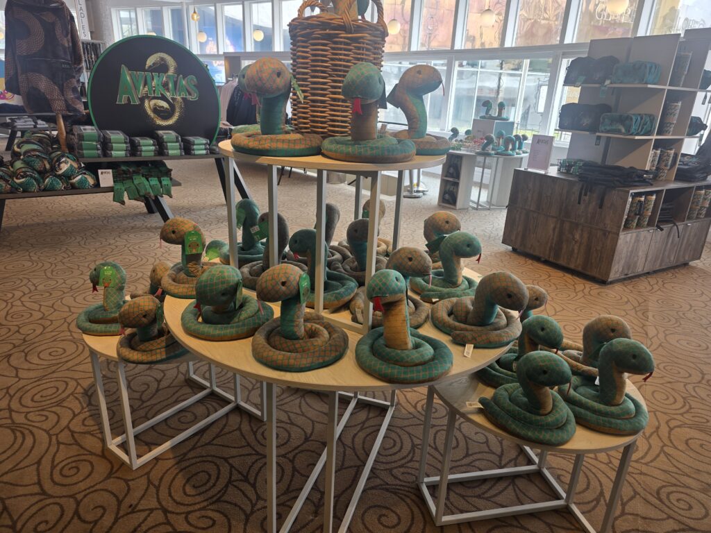 Teal and orange plush snakes coiled on circular display tables in a retail store.