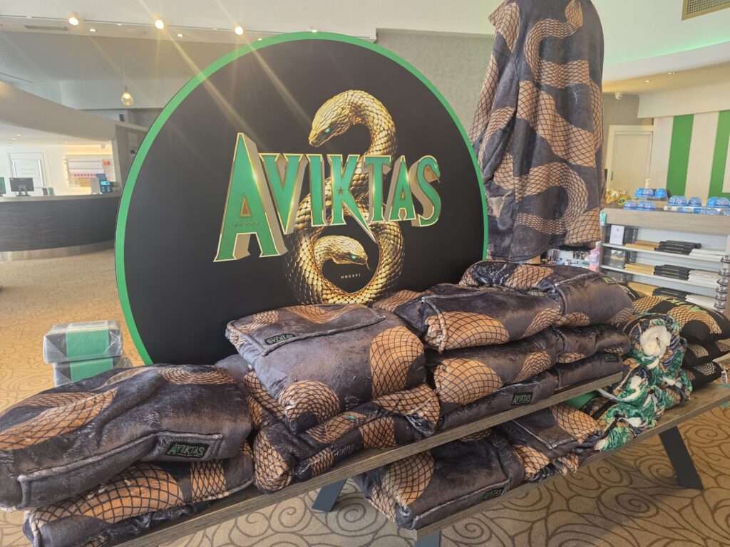 Large circular AVIKTAS display with a gold snake and stacked snake-pattern blankets in a store showroom