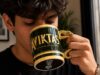 New Aviktas Mug Arrives at Pleasure Beach Resort Young man drinking from a dark green and gold mug with a snake-shaped handle close to his face.