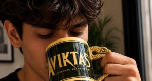 New Aviktas Mug Arrives at Pleasure Beach Resort Young man drinking from a dark green and gold mug with a snake-shaped handle close to his face.