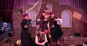 Clacton Pier’s New Pirates Ahoy! Event Draws Huge Crowds During May Half Term Four pirates on a wooden ship set, striking dramatic poses and pointing at the viewer.