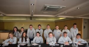Blackpool Pleasure Beach Launches Applications for Its Junior Board of Directors 2026/27 Group of teens in grey hoodies posing around a banquet table in a restaurant or event space, smiling at the camera with glasses and papers on the table.