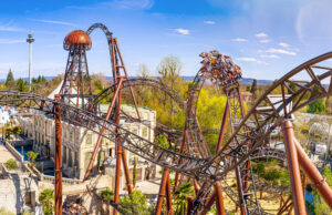 Europa-Park is the fastest growing independent theme park in the Western hemisphere, according to Forbes Magazine Roller coaster cars tilt as a crowd rides a looping steel track against a bright blue sky.