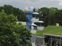 Paultons Park Pirate Ship & Windy Castle Ride Closed for Maintenance Colorful children's amusement ride with blue tower and cloud-shaped baskets, topped by pig characters seen above trees.