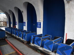 Blackpool Pleasure Beach Responds to Big Dipper Rumours Following Ride Incident Blue roller coaster cars lined up on a track inside a station with arched concrete columns and blue walls, ready for boarding.