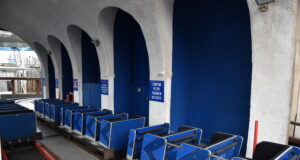 Big Dipper and Pleasure Beach Express Closed at Blackpool Pleasure Beach Blue roller coaster cars lined up on a track inside a station with arched concrete columns and blue walls, ready for boarding.