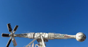 AIR Now Open at Brean Theme Park – Experience the UK’s Only Ride of Its Kind White amusement ride with a long horizontal arm ending in a globe-shaped passenger car, set on a decorative base against a clear blue sky.