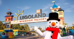 LEGOLAND Windsor Christmas 2026: Everything You Need to Know About This Magical Family Event Legoland Windsor Resort entrance with colorful towers and a snowman mascot in a black top hat and red scarf in the foreground.