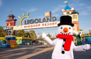 LEGOLAND Windsor Christmas 2026: Everything You Need to Know About This Magical Family Event Legoland Windsor Resort entrance with colorful towers and a snowman mascot in a black top hat and red scarf in the foreground.