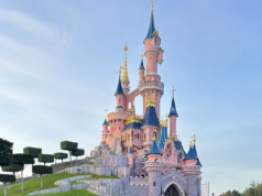 4* Disneyland Paris Hotel Stay, Flights & Optional Park Tickets from Just £89pp Pink fairy-tale castle with blue spires and gold trim atop a rocky hillside against a blue sky.