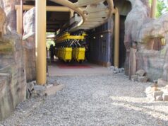 Behind the Scenes Photos of Flight of the Pterosaur at Paultons Park You Need to See Yellow roller coaster train parked on the track inside a rocky, cave-like station area.
