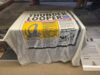 Archives Unlocked at Alton Towers: Step Behind the Scenes of Theme Park History White towel with a vintage newspaper print design spread over a surface, featuring bold black text and a yellow illustration panel.