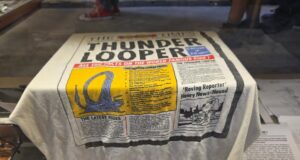 Archives Unlocked at Alton Towers: Step Behind the Scenes of Theme Park History White towel with a vintage newspaper print design spread over a surface, featuring bold black text and a yellow illustration panel.