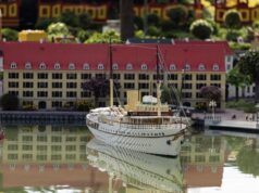 More Than One Million LEGO® Bricks Bring Copenhagen’s Harbour to Life at LEGOLAND® Billund Detailed model ship on calm water with a miniature town featuring red-roofed buildings in the background, reflected in the surface.
