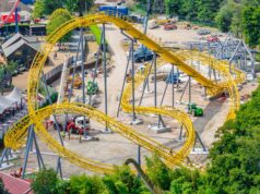 Serpent’s Curse Construction Update: More Track Installed at Paultons Park Aerial view of a yellow roller coaster under construction with scaffolding, dirt ground, and construction vehicles nearby.