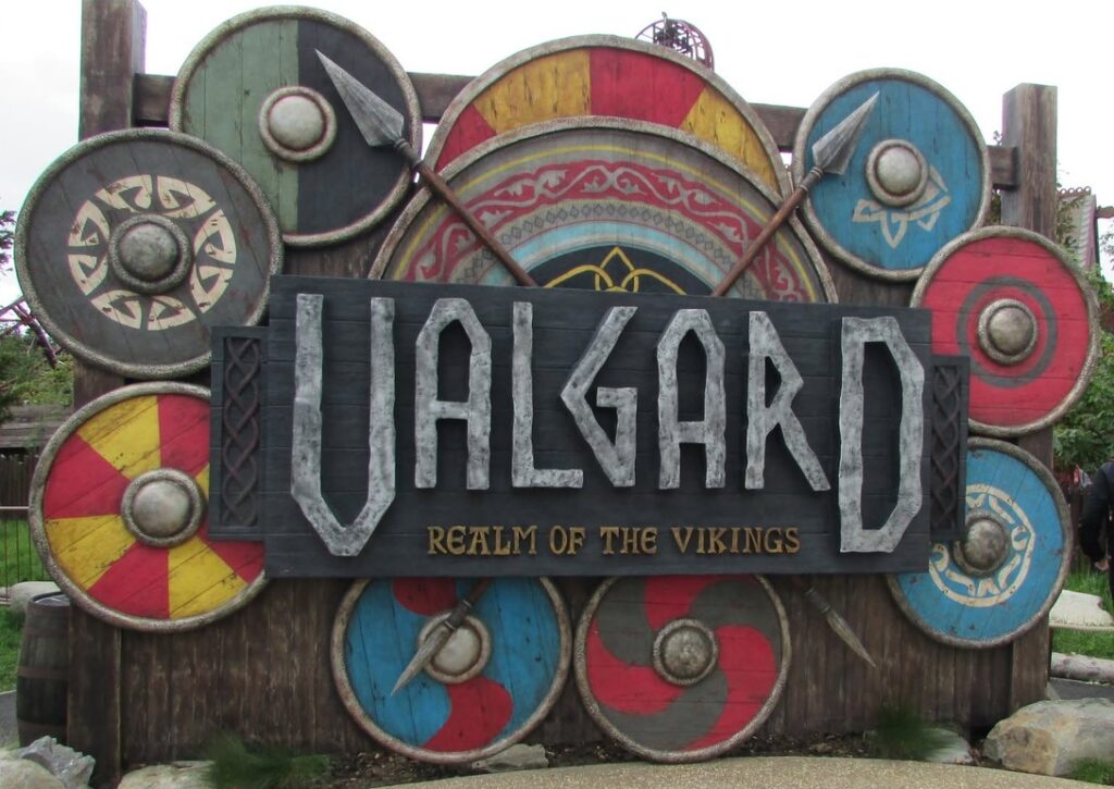 Entrance sign reading 'Ualgard: Realm of the Vikings' with colorful circular shields and spears in a Viking-themed display.