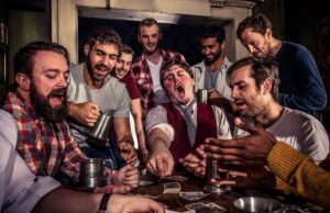 Scarily Good Savings at The York Dungeon Group of men around a cluttered table in a tavern, cheering while playing cards and sharing drinks.