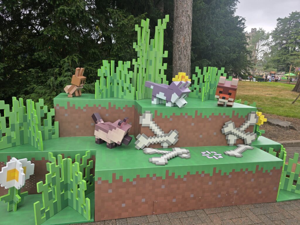 Minecraft-style pixel-art landscape featuring green block vegetation and blocky animal figures on a stepped platform in a parkyard