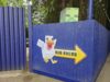 What’s Happening at UK Theme Parks This Weekend (25–26 July 2026) Blue corrugated fence with a Minecraft-style pixel art sign showing a white blocky figure and the yellow 'HUB AHEAD' text.