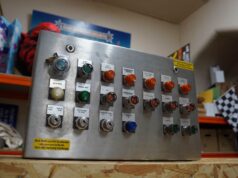 Alton Towers’ Nemesis Control Panel Is Now a £3,000+ Piece of Roller Coaster History Metal control panel with labeled switches and green/orange indicator lights in a workshop setting, including Auto/Manual modes and Lift/Brake labels.