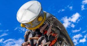 ROTOR Now Open at Crealy Theme Park as First Riders React People in a red roller coaster car upside down mid-loop against a bright blue sky, arms raised in excitement.